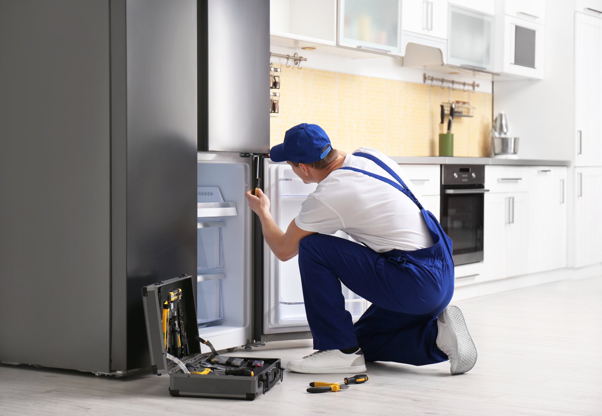 a technician repairing a refrigerator - Best Appliance Repair Charleston