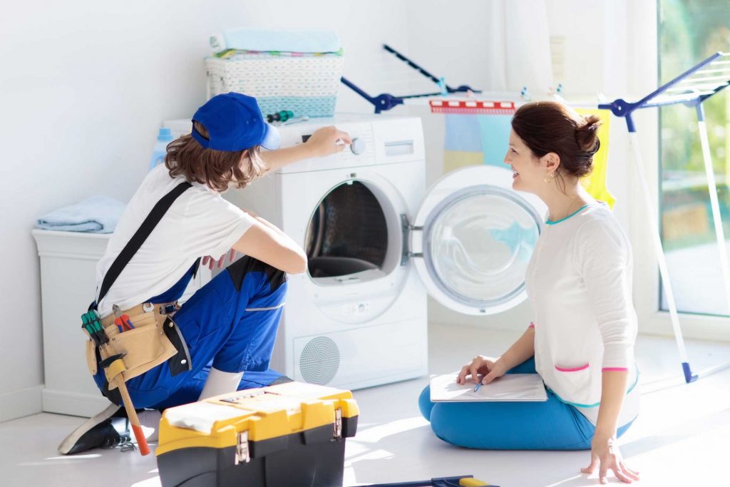 a technician repairing a washer while woman is watching - appliance repair service Charleston