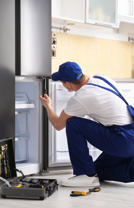 a technician repairing a refrigerator - Best Appliance Repair Charleston